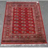 Afghan style machine rug with three rows of nine guls over red ground and border, 173cm x 130cm.