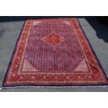 Persian carpet with central red diamond over blue ground, all over geometric floral design,