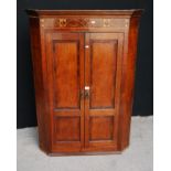 Georgian mahogany and oak corner cupboard, the projected moulded cornice over floral frieze and