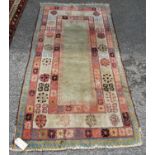 Eastern rug with green ground and rosette border, 182cm x 92cm.