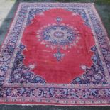 Persian style carpet with central medallion over red ground, spandrels and foliate border, 303cm x