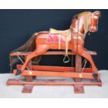 Rocking horse with mane, tail, saddle and tack, raised on cruciform base, by Neil Jackson.