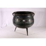 Heavy wrought iron cauldron with twist swing handle raised on three stick feet, 38cm diameter