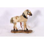 Early 20th century child's pull along toy modelled as a horse on wooden base, 28cm long