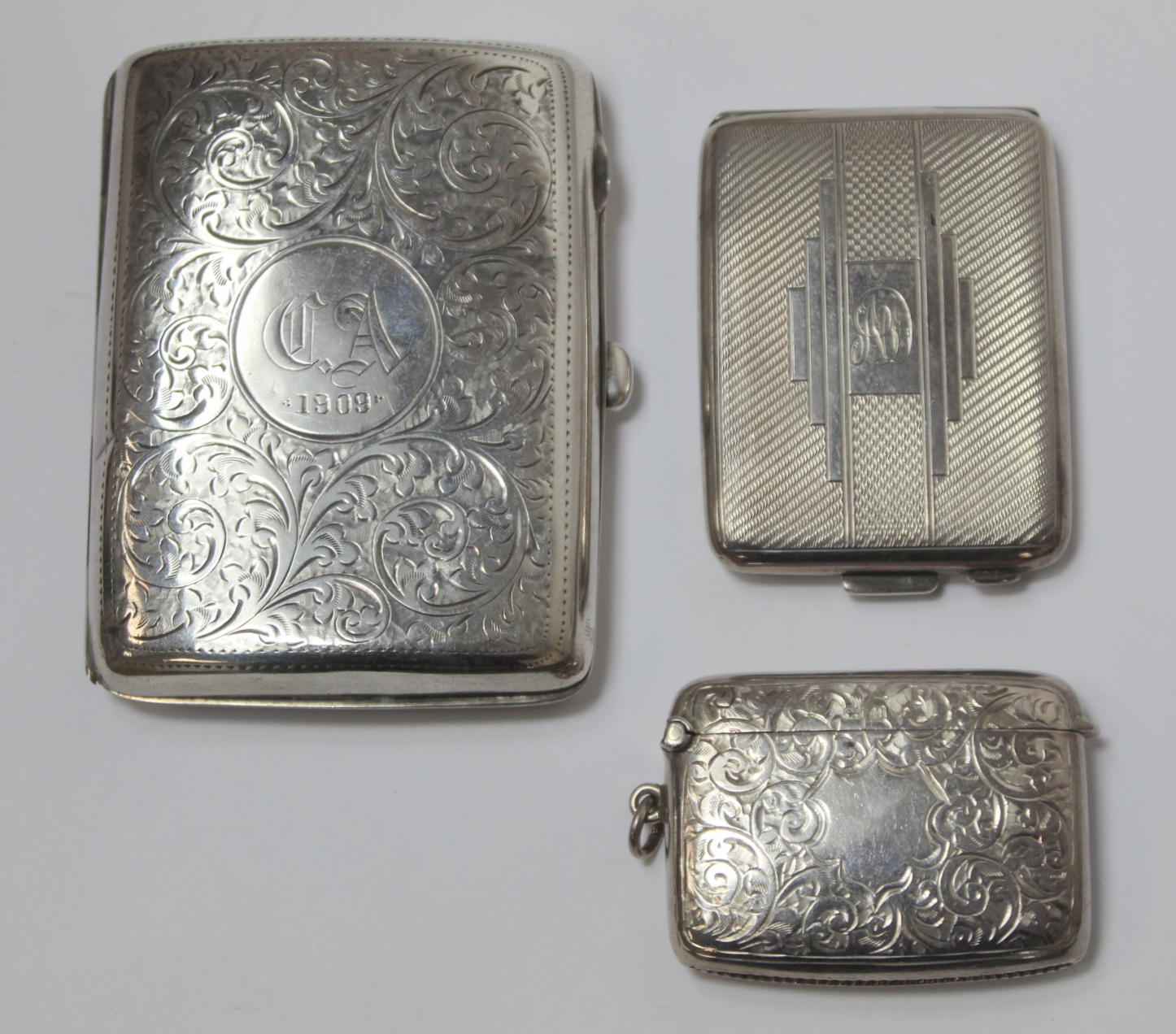 Engraved silver cigarette case, 1909 and two vesta cases. 3½ oz. (3).