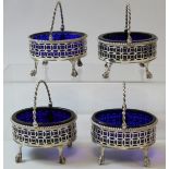 Set of four oval pierced salts, straight sided with swing handles, upon ball and claw feet, crested,