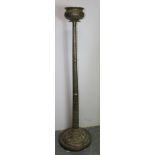 Indian brass floor standing temple lamp, the lotus shaped holder raised on embossed column depicting