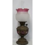 Victorian oil lamp, the cranberry glass reservoir in moulded spelter holder with domed foot, with