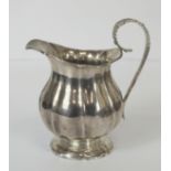 Silver cream jug of fluted baluster form with leafage handle on spreading foot, markers mark rubbed,