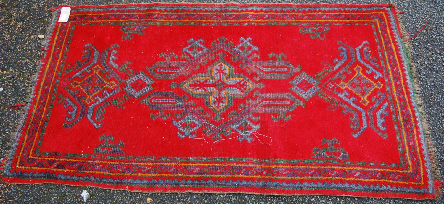 Turkoman rug with three cruciform lozenges, red ground and border, 170cm x 92cm.