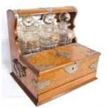 Oak cased tantalus with three decanters and EPNS labels, enclosing glasses, with frieze drawers,