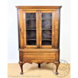 A George III style oak corner cabinet on stand, with two glazed doors enclosing shelves,