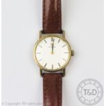 A ladies Omega wristwatch, the yellow metal circular case enclosing silvered dial with batons,