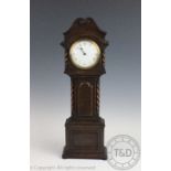 A 1920's oak mantel time piece modelled as a longcase clock, with Roman numeral enamel dial,