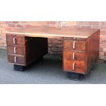 A late Art Deco oak pedestal and composite wood desk, with six drawers, on ebonised plinth bases,