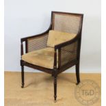 A Regency style mahogany bergere library chair, late 19th / early 20th century, with caned back,