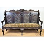 A Victorian carved oak settle, the four panel back decorated with a central female mask and flowers,