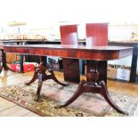 A Regency style mahogany twin pillar dining table, with two spare leaves, on splayed legs,