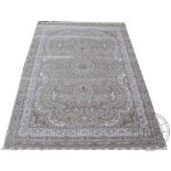A woven bamboo silk carpet, with a floral medallion design against a pale grey ground,