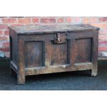 An 18th century rustic oak coffer, with panelled top and front, on stile feet,