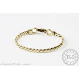 A 9ct yellow gold bangle, designed as a flattened twist with tension, snaffle-type clasp,