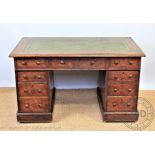 An Edwardian oak pedestal desk, with leather inset top above an arrangement of nine drawers,