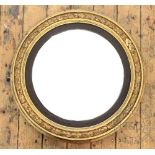 An early 19th century gilt wood and convex circular wall mirror, the frame moulded with leaves,