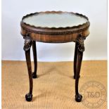 An early 20th century carved walnut circular centre table, the top with a raised serpentine edge,