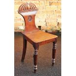 A Regency mahogany hall chair, the shaped back with a painted armorial, above a solid seat,
