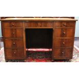 An early 20th century walnut veneered oak desk, with nine drawers, on turned feet,