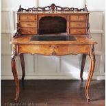 A Victorian carved walnut serpentine bonheur de jour with six drawers above a long frieze drawer