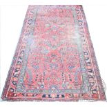 A Caucasian wool rug, worked with a floral pattern against a red ground, 200cm x 108cm,