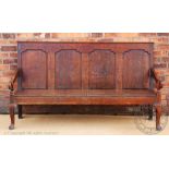 A George III oak settle, with four panelled back above a later solid seat,