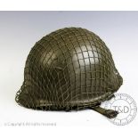 A 20th century military helmet, with green painted exterior and camoflage netting,