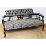 An Edwardian carved walnut salon settee, with button back blue foliate upholstery, on cabriole legs,