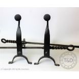 A pair of Arts and Crafts style cast iron fire dogs, with two fire tools with entwined handles,