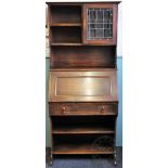 An Edwardian oak students desk, with lead glazed door above slope, drawer and shelves,