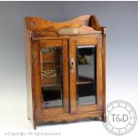 An George V oak smokers compendium, circa 1925, the two door cabinet revealing a fitted interior,