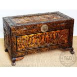 A Chinese carved camphor wood blanket box, decorated with panels of ships, and foliage,