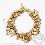 A yellow metal bracelet hung with numerous charms, to include, bean, acorn, fish, a carriage,