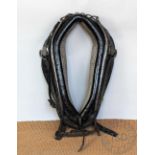 A vintage black and brass horse collar, with steel fittings and brass acorn shaped terminals,