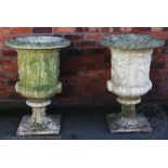 A pair of reconstituted stone garden planters, modelled as urns with mask head handles,