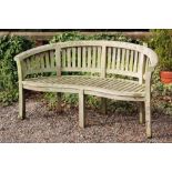 A curved garden bench, with serpentine slatted seat,