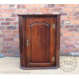 A George III oak corner cabinet, with panelled door,