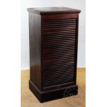 An early 20th century mahogany filing cabinet, with tambour enclosing shelves on plinth base,