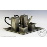 An Art Deco planished pewter tea service comprising; a tea pot, 15cm high, hot water jug, 15cm high,