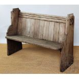 A bleached pine pew with solid seat on standard end supports,