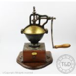 A large cast iron Peugeot Freres coffee grinder, on an oak base and with an integral drawer,
