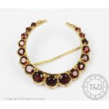 A garnet set crescent brooch in 9ct gold, designed as seventeen graduated garnets,