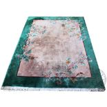 A Chinese wool carpet, worked with a floral design against a green ground,